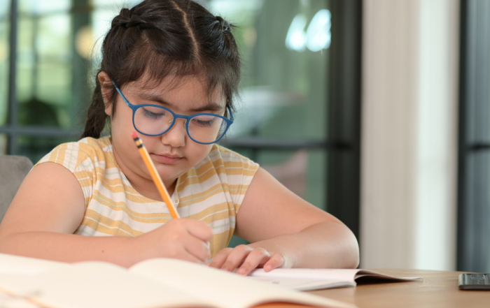 kid with learning disability writing with a pencil on a book
