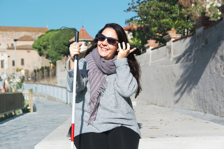 Person who is blind walking outdoors with a white cane